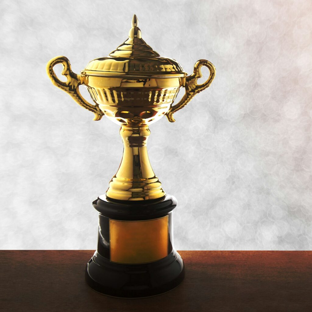 Golden trophy atop a wooden tabletop with an abstract white bokeh background